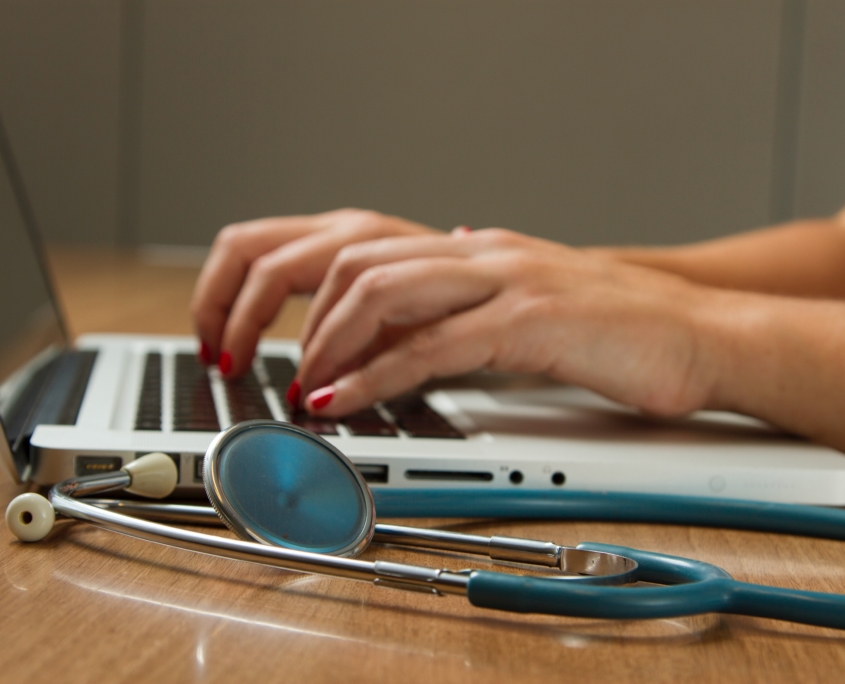 hands typing on laptop with stethoscope