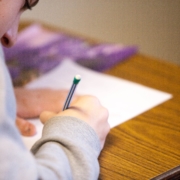 student writing on paper hunched over desk