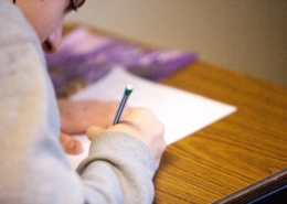 student writing on paper hunched over desk