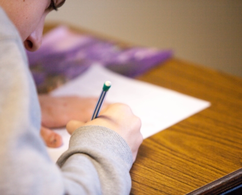 student writing on paper hunched over desk