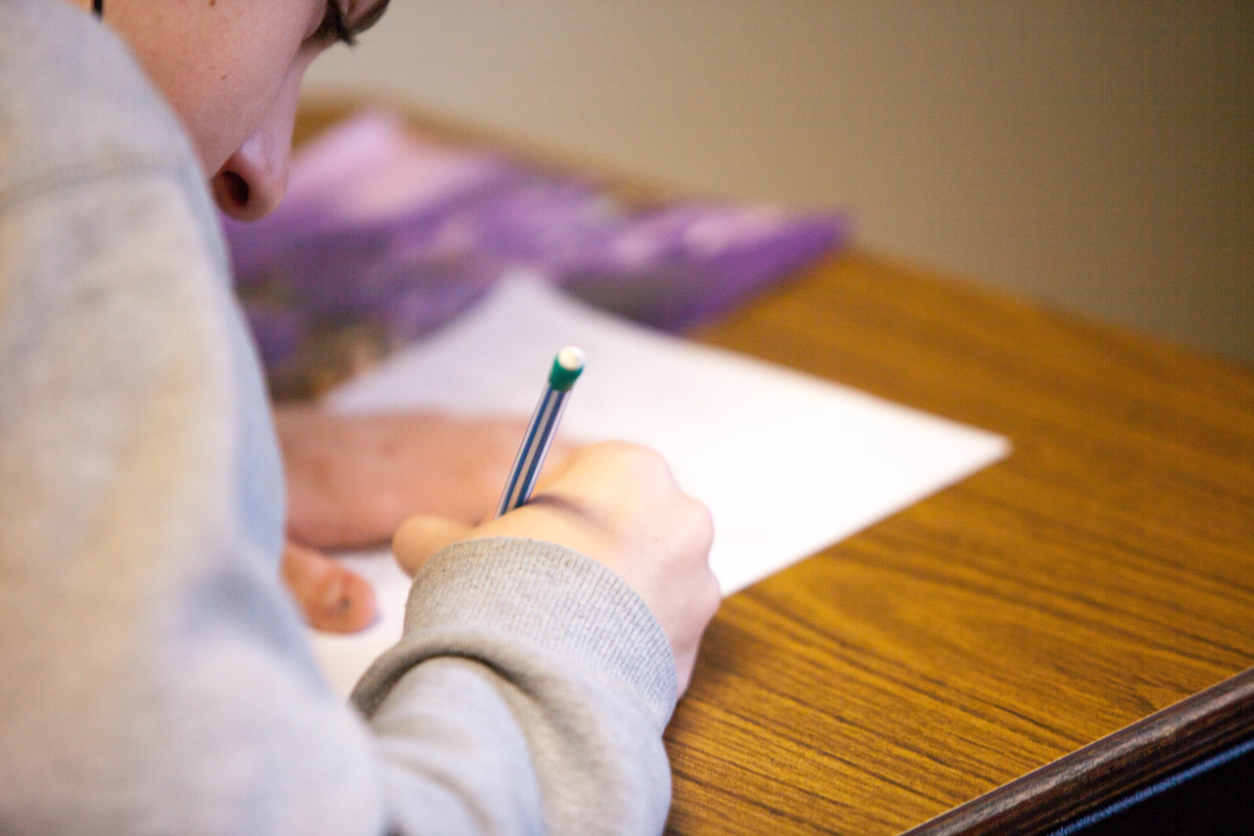 student writing on paper hunched over desk