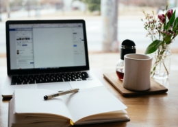 open notebook and coffee mug in front of laptop open for studying