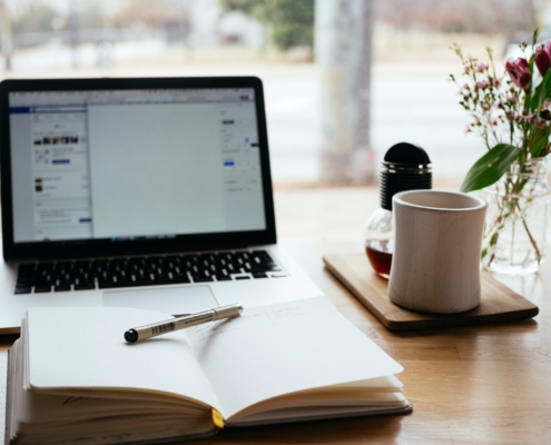 open notebook and coffee mug in front of laptop open for studying