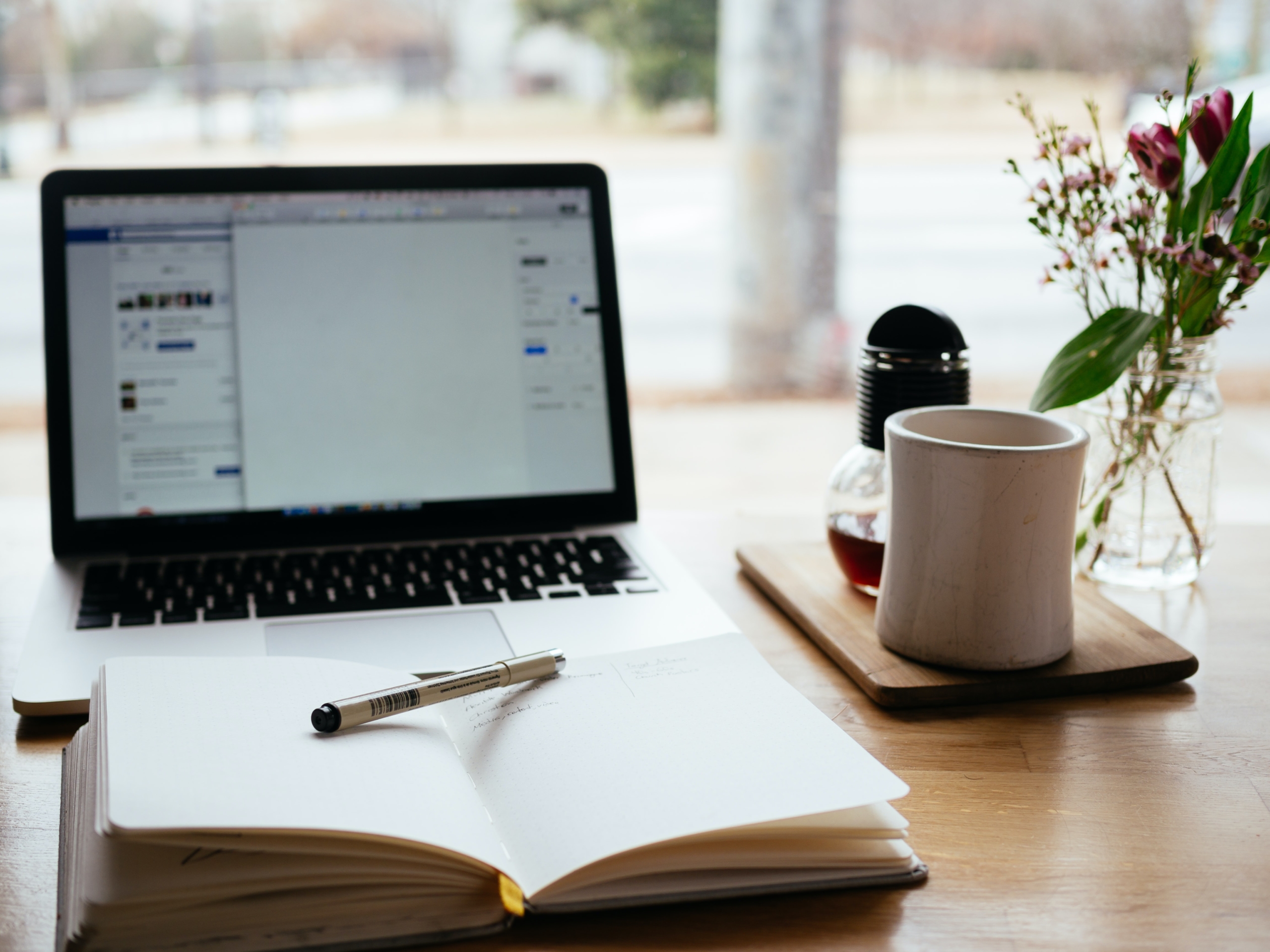 open notebook and coffee mug in front of laptop open for studying