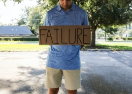 Man holding sign that says "failure"