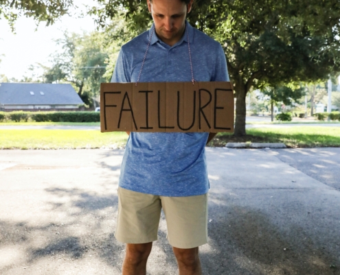Man holding sign that says "failure"