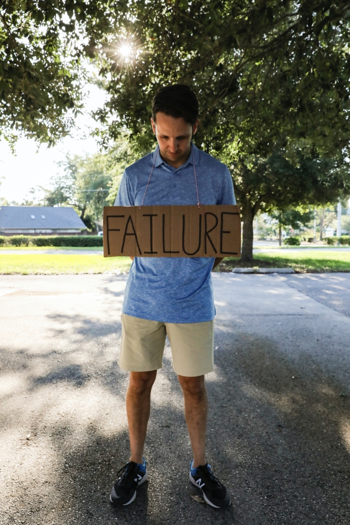 Man holding sign that says "failure"