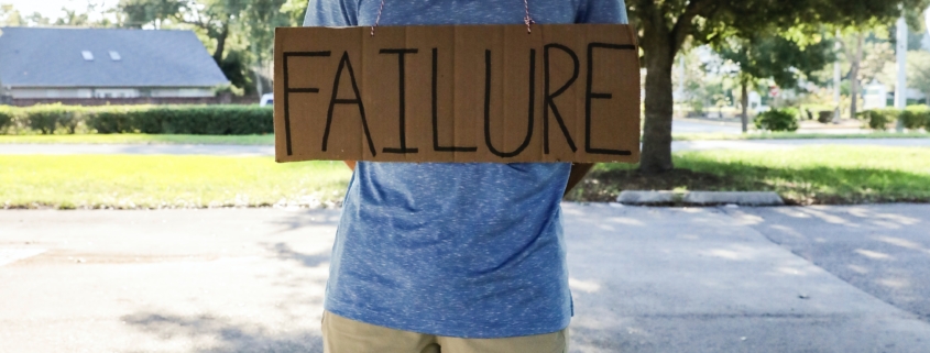 Man holding sign that says "failure"