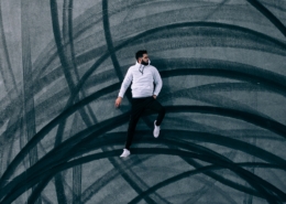 man lying on road with burnout marks