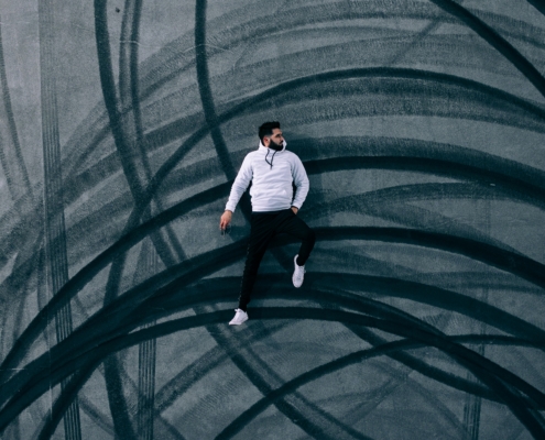 man lying on road with burnout marks